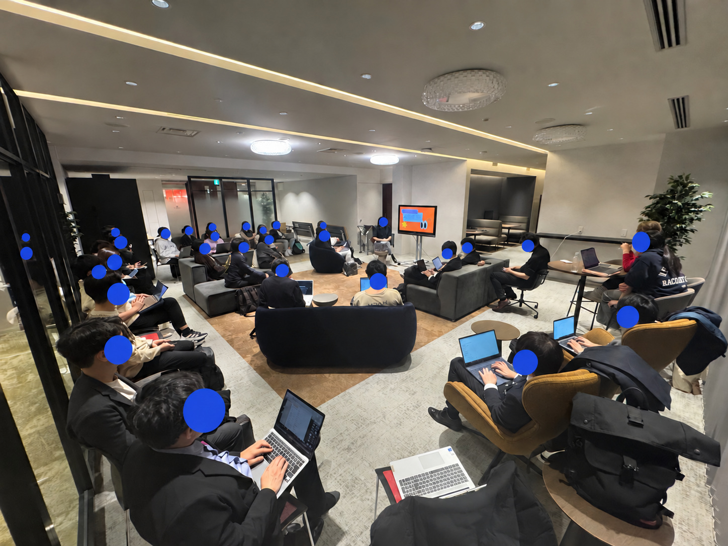 A wide view of the design thinking lecture; faces covered with blue circles.